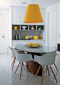 an image of a dining room table and chairs with yellow lamps on the wall above it