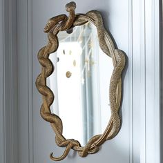 a mirror hanging on the side of a door with a snake design in front of it