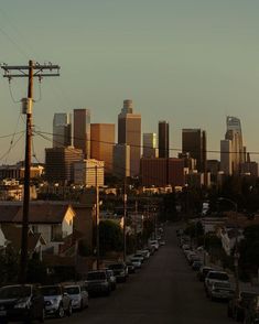 cars parked on the side of a road in front of a large cityscape