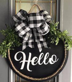 a black and white wreath with the word hello painted on it hanging from a door