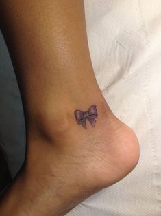 a small purple bow tattoo on the foot