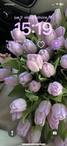 a bouquet of pink tulips sitting in the center of a car dash board