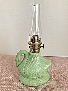 an old fashioned lamp with a green swan on it's body and a gold crown on its head