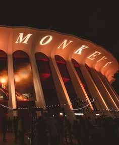 people are standing in front of the neon sign for monkeytown at night with lights on