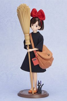 a doll holding a broom with a black cat on it's back and wearing a red bow