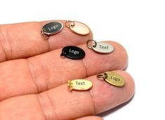 a person's hand holding five different types of personalized charms on their fingers