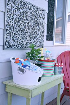 a red chair sitting on top of a wooden table next to a white bucket filled with drinks