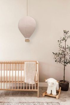 a baby's room with a crib, rocking horse and potted plant