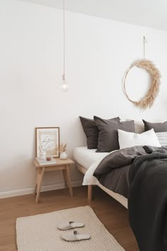 a bedroom with white walls and wood flooring is pictured in this image, the bed has dark gray linens on it