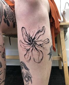 a woman's legs with tattoos on them and flowers in the middle of her leg