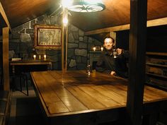 a wooden table topped with chess pieces in front of a stone wall and ceiling light