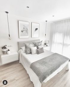 a white and gray bedroom with pictures on the wall above the bed, along with two nightstands