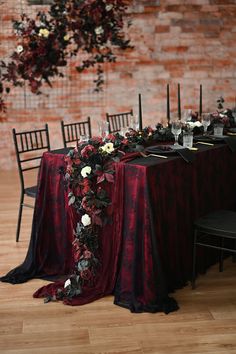 the table is set with black and red linens, candles, and white flowers