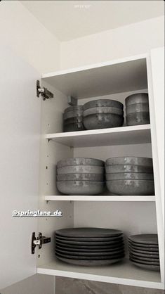 an open cabinet with plates and bowls on it