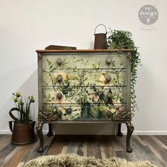 an old dresser with flowers painted on it and plants growing out of the top drawer