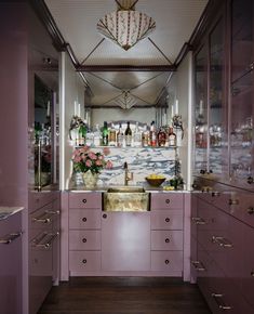 a kitchen with pink cabinets and white counter tops in front of a chandelier