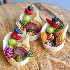 three small bowls filled with food on top of a wooden table