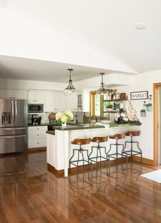 a kitchen with an island and bar stools next to the stove top oven, refrigerator and dishwasher