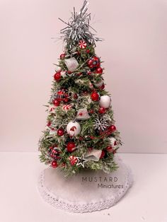 a small christmas tree with ornaments on it's base and snowflakes around the top