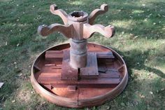 a wooden table with a metal vase on top in the middle of some green grass