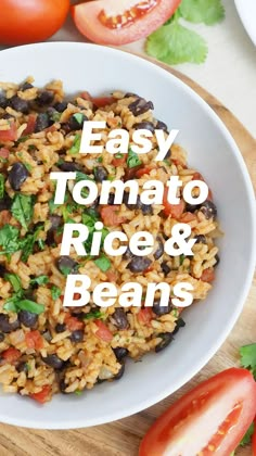 a white bowl filled with rice and black beans next to tomatoes on a cutting board