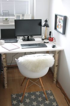 a desk with two computers on it and a rug in front of the computer monitor