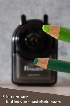 two green pencils are next to a camera