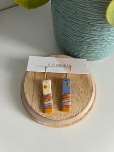 a pair of wooden earrings sitting on top of a table next to a potted plant