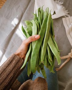 a person holding some green beans in their hands