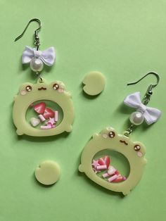 two pairs of earrings with bows on them sitting next to each other in front of a green background