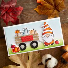 a card with an image of a gnome driving a wagon filled with pumpkins and acorns