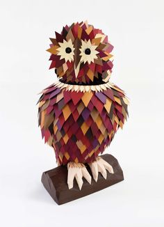 an origami owl sitting on top of a wooden stand with its eyes open