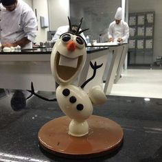 a frozen food character statue on a counter in a kitchen with two chefs behind it