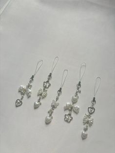 five pairs of dangling earrings with pearls and bows on them, all in different shapes