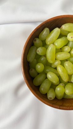 green grapes in a wooden bowl on a white sheet