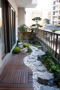 a small balcony with rocks and plants on the floor, along with wooden decking