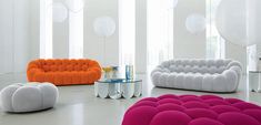 an assortment of colorful couches and tables in a room with balloons hanging from the ceiling