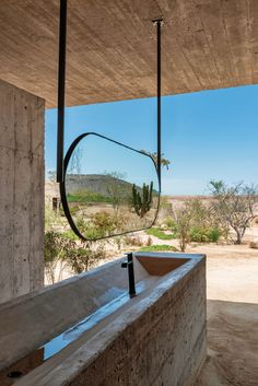 an outdoor bathtub with a circular mirror hanging from it's side