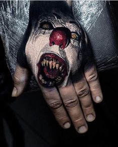 a hand with a scary clown face painted on it