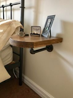 a wooden table sitting on top of a bed next to a metal frame and lamp