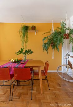 a dining room with yellow walls and red chairs, an orange table cloth on the wooden floor