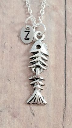 "This listing is a for a hand stamped initial necklace featuring a 1\" x 1/2\" silver plated pewter fish bones charm & 3/10\" x 1/5\" stainless steel initial pendant. The silver plated chain is 18\" long, but can be made to your desired length- see last photo in listing. Please indicate the chain length you would like in the 'notes to seller' section at checkout. Message me with any questions, thank you! Add an initial to any necklace: https://www.etsy.com/listing/170461597/add-an-initial?re Bones Necklace, Fish Bone Necklace, Skeleton Jewelry, Fish Skeleton, Fish Bones, Dead Fish, Fish Jewelry, Bone Jewelry, Fish Bone