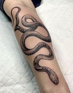 a black and white snake tattoo on the arm