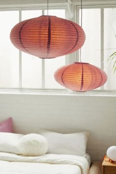 two red lanterns hanging from the ceiling above a bed in a room with white walls