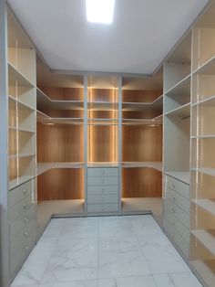 an empty walk in closet with lots of shelves and drawers on the wall, all white marble flooring