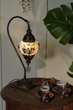 a lamp that is sitting on top of a table next to cups and saucers