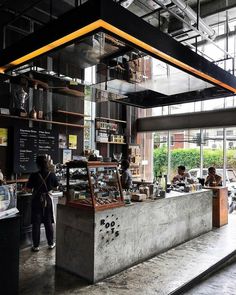 the inside of a restaurant with people sitting at tables and standing in front of it