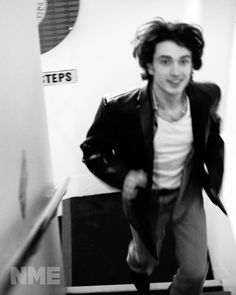 black and white photograph of a young man walking down the stairs with his jacket on