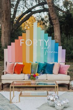 a couch sitting in front of a rainbow colored wall with pillows on top of it