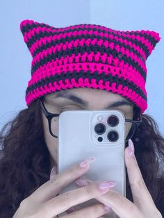 a woman taking a selfie in front of her cell phone wearing a cat hat